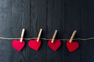 Koyu arka plan üzerinde clothespins ile kırmızı Kalpler