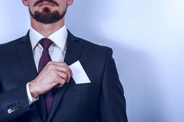 Bearded man in dark suit removes card to pocket