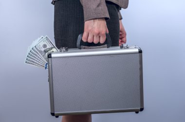 Woman in suit carries metal briefcase with dollars