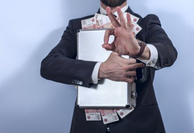 Man in suit holds metal briefcase full of money