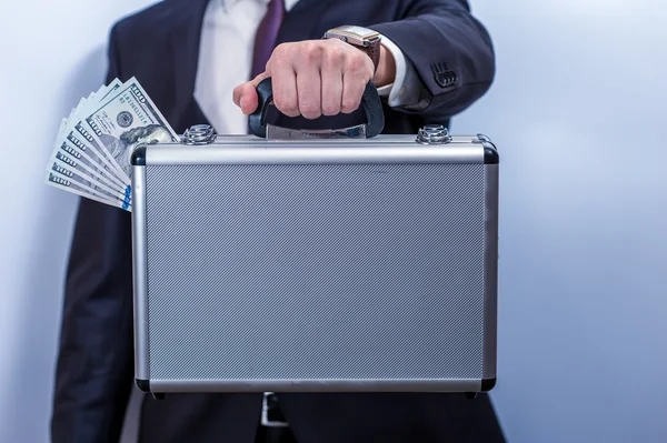 Man in pak houdt metalen koffertje met dollars — Stockfoto
