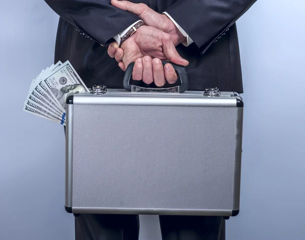 Man holds a suitcase with money behind the back — Stockfoto