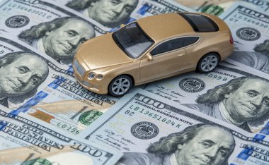 Golden toy car on the background of banknotes