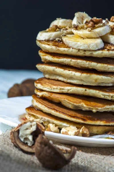 Homemade pancakes with banana slices, honey and walnuts on wooden background. — Stock Photo, Image