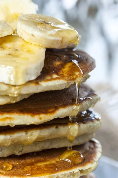 Stack of homemade pancakes with banana slices and honey, close up. — Stock Photo, Image