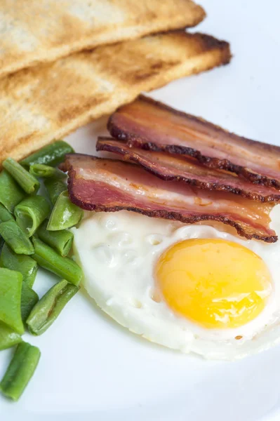 Stekt ägg, bacon, gröna bönor och skålar på ljus bakgrund. Engelsk frukost. — Stockfoto