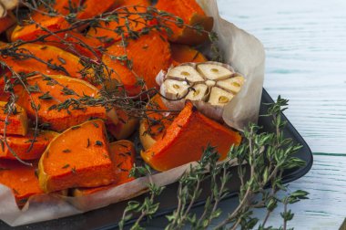 Baked pumpkin with thyme, olive oil and garlic on baking tray. Horizontal view. Vegetarian food.