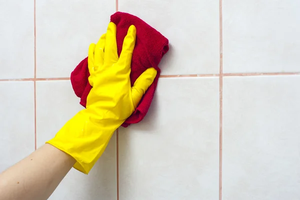 Hand in yellow glove washing tile with special rag. Cleaning concept.