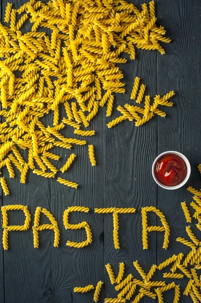Fusilli паста і Кубок томатного соусу на старих дерев'яних фоні. Італійська кухня. — стокове фото
