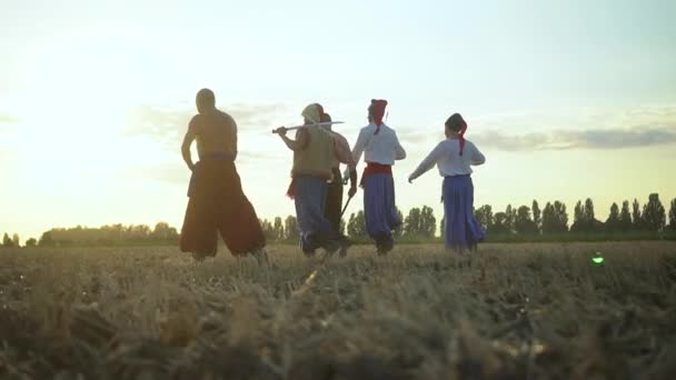 Grupo de hombres cosacos en ropa tradicional balanceándose y girando shashkas afilados contra el cielo nublado puesta de sol — Vídeos de Stock