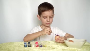 Mutlu Paskalyalar. Güzel beyaz çocuk yumurtaları boyayıp süslüyor..