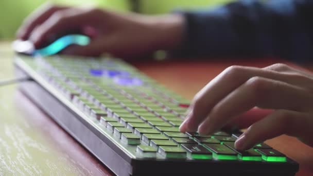 Jovem jogador joga um jogo de vídeo usa teclado iluminado de jogos. — Vídeo de Stock
