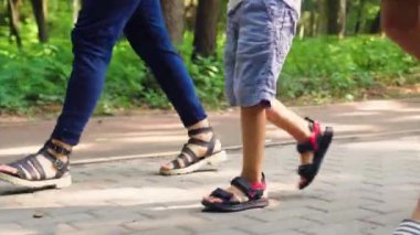 Üç kişilik bir aile parkta yürüyor.