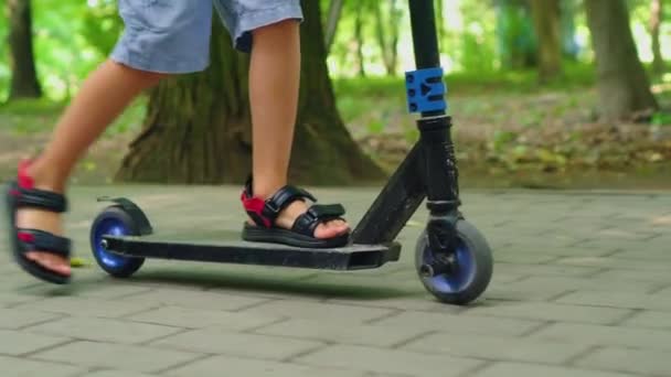Хлопчик їде на скутері в міському парку — стокове відео