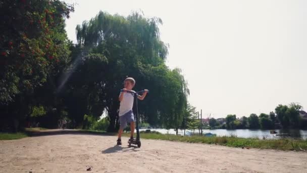 En pojke åker skoter i en stadspark — Stockvideo