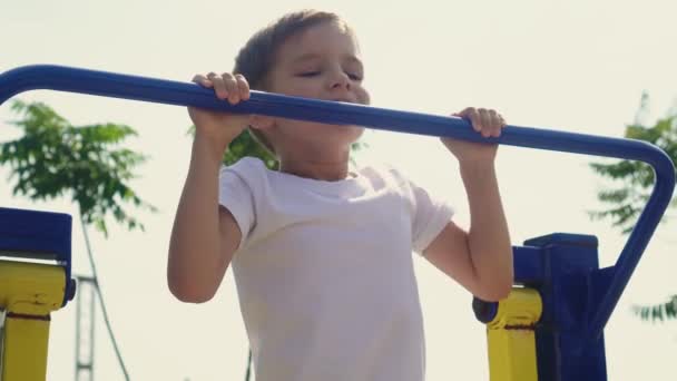 Mały chłopiec uprawia sport na placu zabaw. — Wideo stockowe