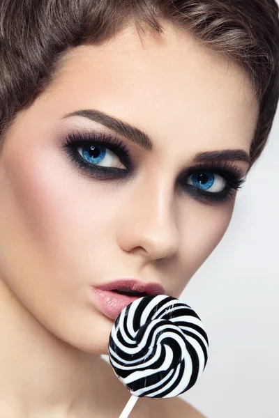 Vrouw met rokerige ogen en gestreepte lolly — Stockfoto
