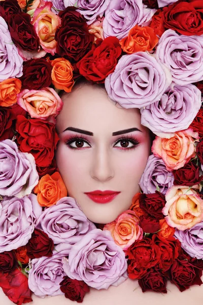 Femme avec des roses colorées autour du visage — Photo