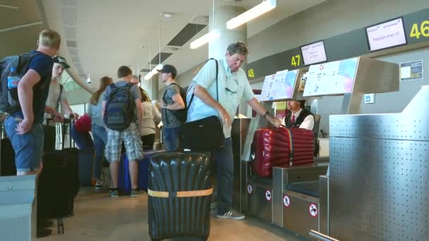 Pasajeros de aerolíneas registrándose en un mostrador de aerolíneas — Vídeo de stock