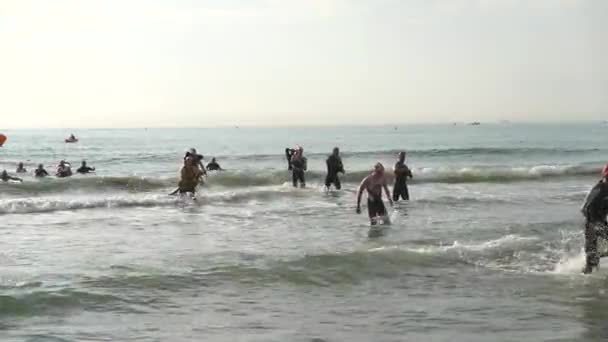 Los triatletas salen del agua de la parte de natación de un triatlón — Vídeos de Stock