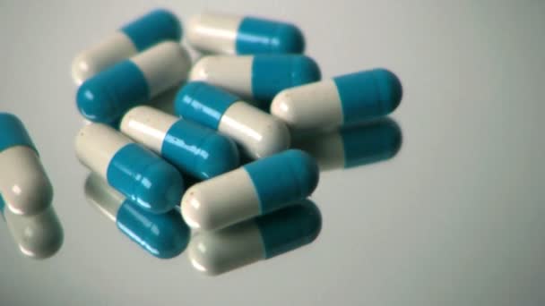 Blauwe en witte pillen draaien op glas draaitafel — Stockvideo