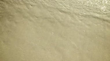 Sakin dalgalar art arda kumlu kıyıda yıkama