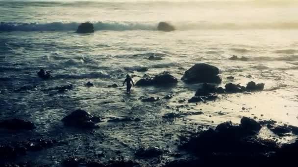 Surfer hoofden uit aan golven bij zonsondergang — Stockvideo