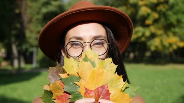 Retrato de uma bela mulher sorridente do Oriente Médio segurando um buquê de folhas coloridas em suas mãos. Folhas de outono no parque de outono. Meados de outono, decíduo, bela paisagem do parque no — Vídeo de Stock