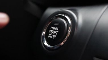 Adam arabadaki düğmeye basıyor. Bir düğmeye basarak motoru çalıştır. Yakın plan..