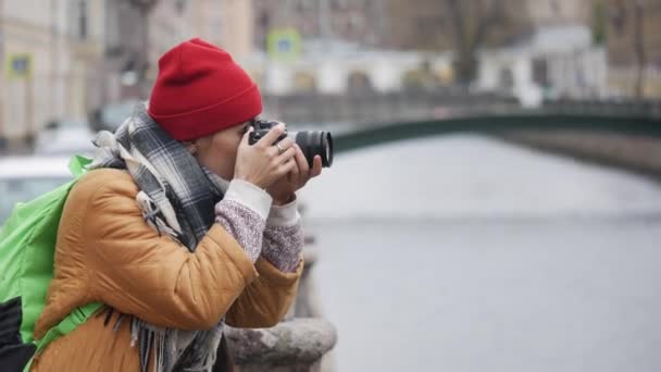 Wisatawan muda dari timur tengah mengambil gambar sambil berdiri di dekat sungai pada hari musim gugur yang dingin. — Stok Video