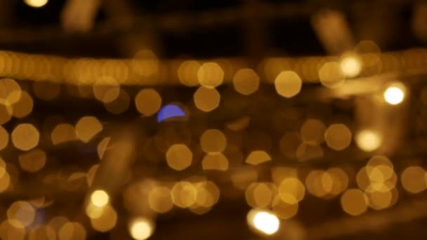 Defocused holiday lights glowing in darkness in night city streets. Abstract christmas background in bokeh. Blinking garland in blur. Out of focus — Stock Video