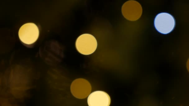 Defokussierte Weihnachtslichter, die in der Dunkelheit in den nächtlichen Straßen der Stadt leuchten. Abstrakter weihnachtlicher Hintergrund in Bokeh. Blinkende Girlanden in Unschärfe. Unscharf — Stockvideo
