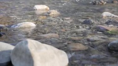 Taşlı küçük bir nehir. Bir dağ deresindeki su taşların etrafında akar. Kayalık kıyılar arasında akan. Yakın plan..