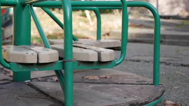 Old metal carousel for children is moving. Empty abandoned city with a playground. Empty swing. Concept of child abduction. Kidnapping — Stock Video