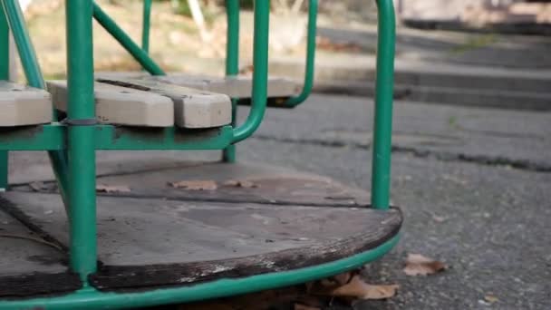 O velho carrossel de metal para crianças está se movendo. Cidade abandonada vazia com um parque infantil. Balanço vazio. Conceito de rapto de crianças. Rapto. — Vídeo de Stock