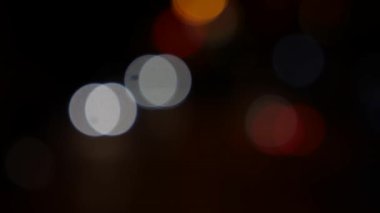 Gecenin karanlığında bulanık arkaplanda güzel, ışıltılı bir bokeh. Şehir caddesindeki araba ışıklarından yuvarlak renkli bokeh parlıyor. Bulanık yüzünden bulanık. Odaklanmamış şehir ışıkları. Trafik sıkışıklığı. Soyut