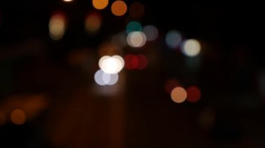 Gecenin karanlığında bulanık arkaplanda güzel, ışıltılı bir bokeh. Şehir caddesindeki araba ışıklarından yuvarlak renkli bokeh parlıyor. Bulanık yüzünden bulanık. Odaklanmamış şehir ışıkları. Trafik sıkışıklığı. Soyut