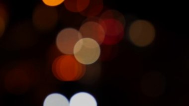 Gecenin karanlığında bulanık arkaplanda güzel, ışıltılı bir bokeh. Şehir caddesindeki araba ışıklarından yuvarlak renkli bokeh parlıyor. Bulanık yüzünden bulanık. Odaklanmamış şehir ışıkları. Trafik sıkışıklığı. Soyut
