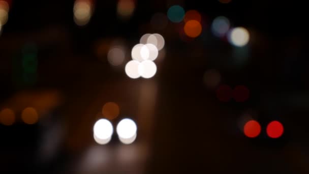Ночью на темном размытом фоне скользит боке. Круглый красочный боке сияет от автомобильных огней на городской улице. Не в фокусе с расплывчатым. Несфокусированные огни города. Пробки на дорогах. Абстрагируясь — стоковое видео