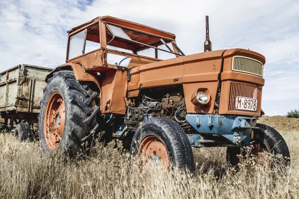 Покинуті на полі ферми трактор — стокове фото