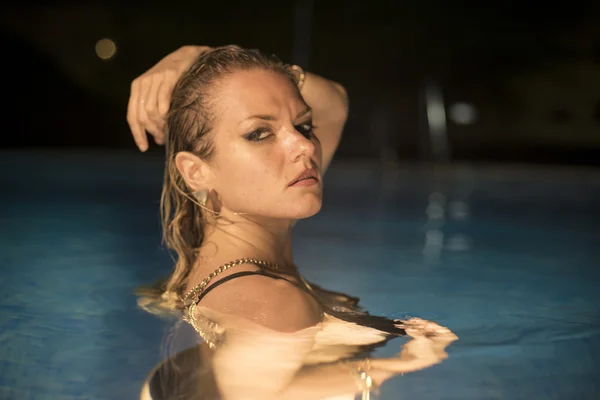 Femme dans une piscine la nuit — Photo