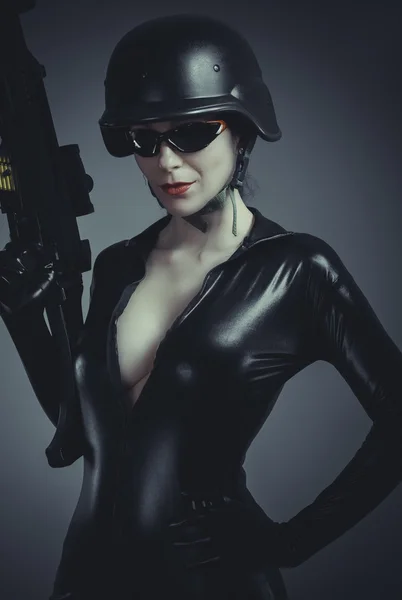 Žena v latexové kombinéze s těžkou zbraní — Stock fotografie