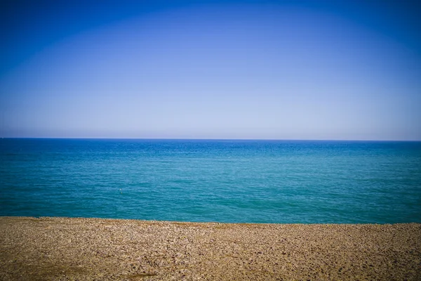 Пляж с галькой и ясным небом — стоковое фото