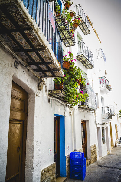 Colorful flower pots on balconies of ancient houses in town along Mediterranean coast