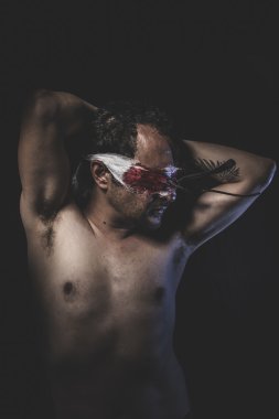 Kanla ıslanmış gözleri bağlı olan çıplak adam