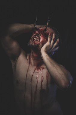 Kanla ıslanmış gözleri bağlı olan çıplak adam