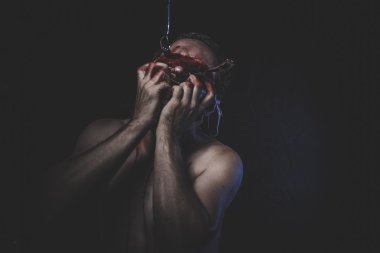 Kanla ıslanmış gözleri bağlı olan çıplak adam