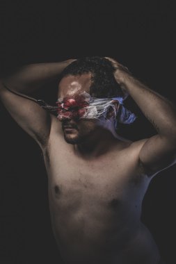 Kanla ıslanmış gözleri bağlı olan çıplak adam