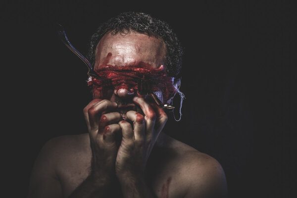 Naked man with blindfold soaked in blood