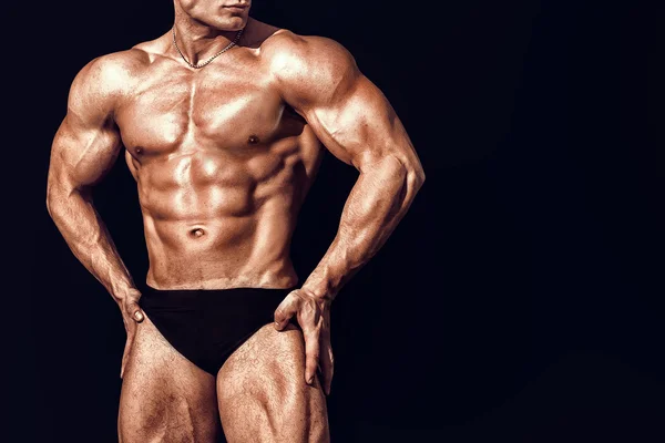 Strong Athletic Man showing six pack abs. closeup isolated over black background Stock Photo